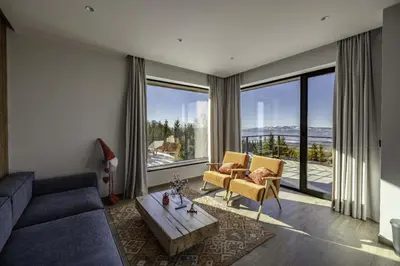 a living room with a couch and a large window at Chalet 1600 Kopaonik in Kopaonik