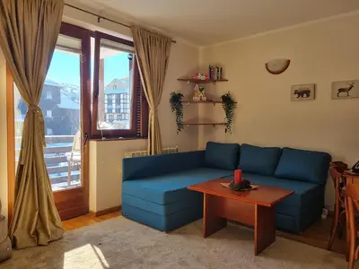 a living room with a blue couch and a table at Apartman Vrh,Kopaonik in Kopaonik