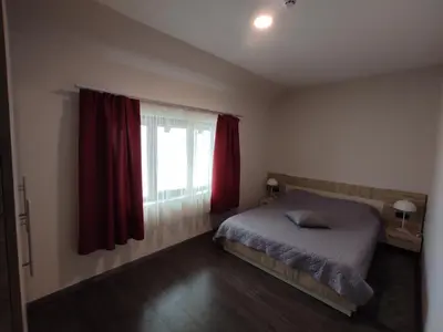 a bedroom with a bed and a window with red curtains at Apartman K25 Milmari in Kopaonik