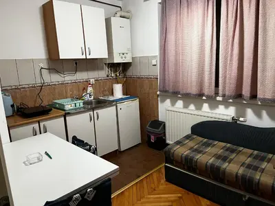 a room with a bed and a kitchen with white cabinets at Pufen Apartments - Nis in Niš