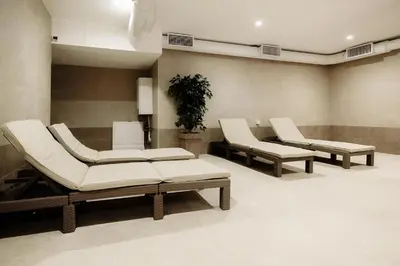 a waiting room with two white chairs and a plant at Boggi Apartman, Kopaonik in Kopaonik