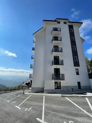 a building on top of a mountain with a parking lot at Boggi Apartman, Kopaonik in Kopaonik