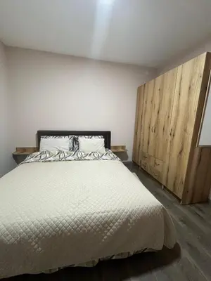 a bedroom with a white bed and wooden cabinets at Apartman KVINS in Kruševac