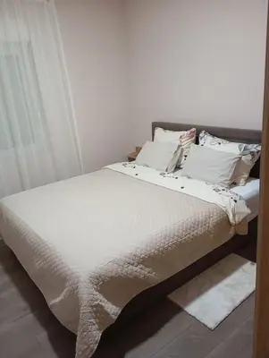 a bedroom with a bed with white sheets and pillows at Apartman KVINS in Kruševac