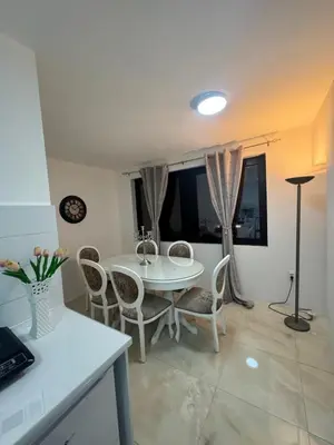 a dining room with a white table and chairs at Best Deal Suite in Niš