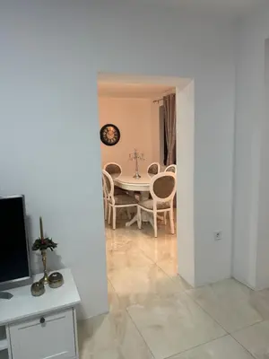 a living room with a table and chairs and a television at Best Deal Suite in Niš