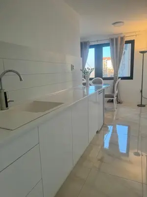 a white kitchen with white cabinets and a sink at Best Deal Suite in Niš