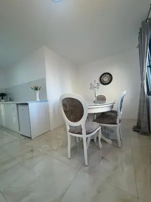a white dining room with a table and chairs at Best Deal Suite in Niš