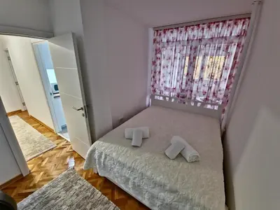 a small bedroom with a bed with slippers on it at Apartman Leskovac in Leskovac