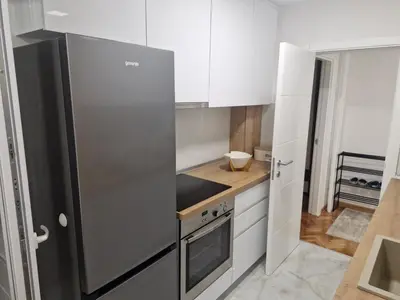 a kitchen with white cabinets and a stainless steel refrigerator at Apartman Leskovac in Leskovac