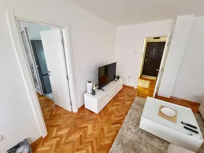 a living room with a television on a white wall at Apartman Leskovac in Leskovac