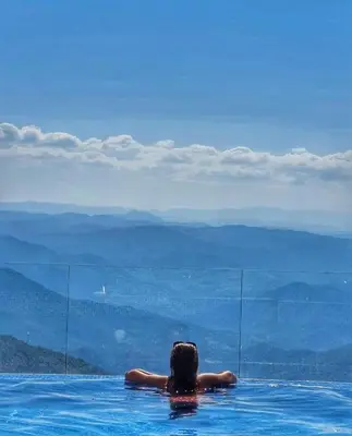 a person in a swimming pool looking at the mountains at Apartments Kos - Milmari Resort in Kopaonik