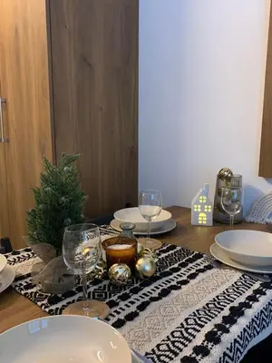 a table with plates and glasses and a christmas tree on it at Apartman Glečer Vila Bela Reka in Brzeće