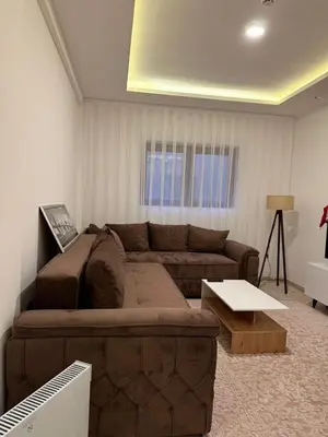 a living room with a brown couch and a table at Milmari kop in Raška