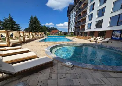 a swimming pool with lounge chairs and a hotel at Planinski kutak Residence Hill in Kopaonik