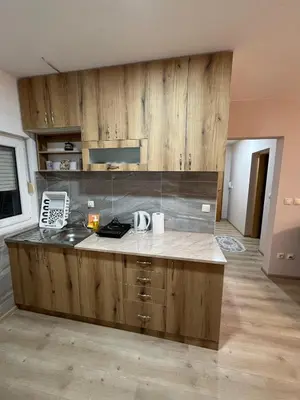 a kitchen with wooden cabinets and a counter top at Apartman KVINS 1 in Kruševac