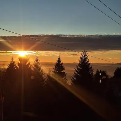 a sunset with the sun rising over the trees at Hera Kopaonik in Kopaonik