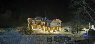 a large house with lights in the snow at night at Vučja reka in Crni Vrh