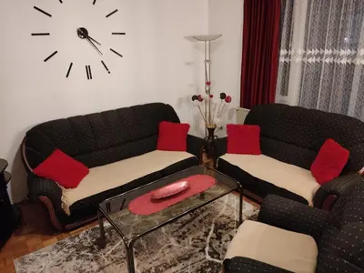 a living room with two couches and a clock on the wall at Apartman Trijumf in Vrnjačka Banja