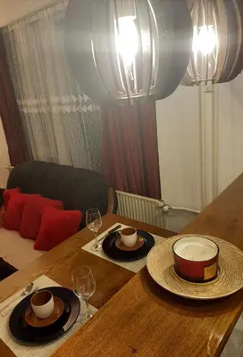 a wooden table with two plates and wine glasses on it at Apartman Trijumf in Vrnjačka Banja