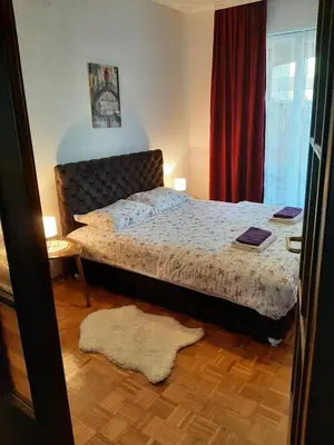 a bedroom with a bed and a red curtain at Apartman Trijumf in Vrnjačka Banja