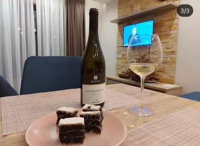 a bottle of wine and a plate of cake and wine glass at Milmari GOGA APARTMAN in Kopaonik