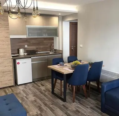 a kitchen with a table and blue chairs in a room at Milmari GOGA APARTMAN in Kopaonik
