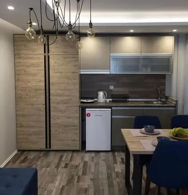 a kitchen with a refrigerator and a table with blue chairs at Milmari GOGA APARTMAN in Kopaonik