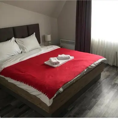 a bed with a red blanket and two towels on it at Milmari GOGA APARTMAN in Kopaonik