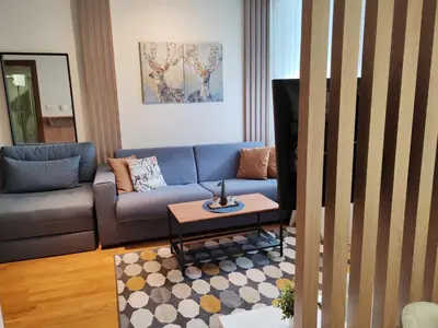 a living room with a blue couch and a table at Brzece lux apartman in Brzeće