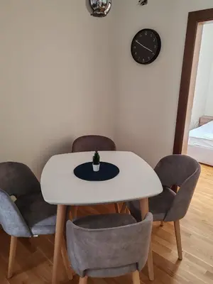 a dining room with a white table and chairs at Brzece lux apartman in Brzeće