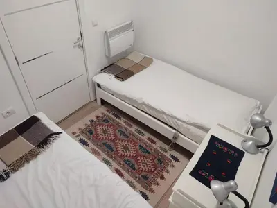 a small room with two beds and a rug at Kopaonik apartman Miklušev in Kopaonik