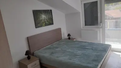 a bedroom with a bed with a blue comforter and a window at Četiri dragulja in Soko Banja