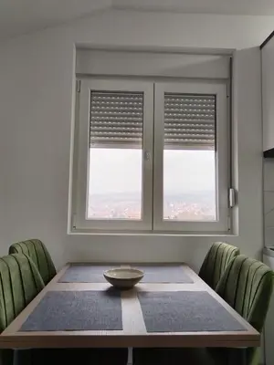 a dining room with a table and two windows at Četiri dragulja in Soko Banja
