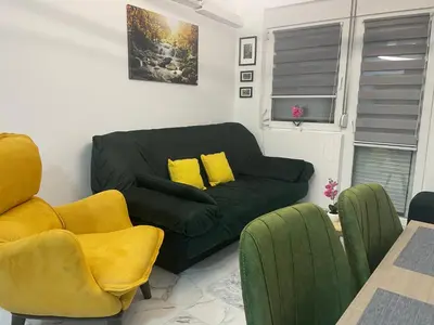 a living room with a black couch and yellow chairs at Četiri dragulja in Soko Banja