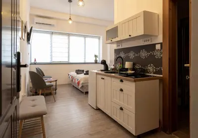 a room with a kitchen and a bedroom with a bed at Encanto room in Niš