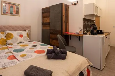 a bedroom with a bed and a small kitchen at Encanto room in Niš