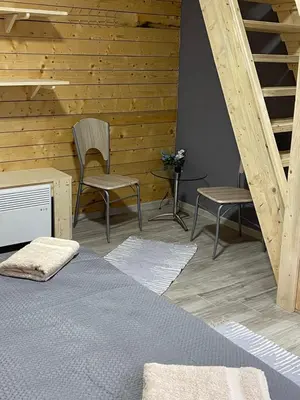 a bedroom with a bed and two chairs and stairs at Šumska vila Gašić in Kopaonik
