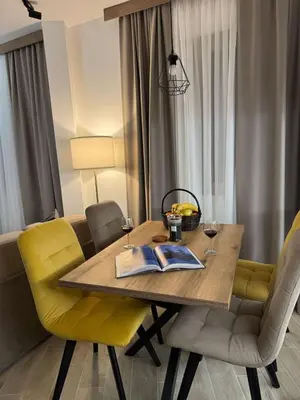a dining room table with yellow chairs and a book on it at Friends Apartmani - Broj 2 in Raška