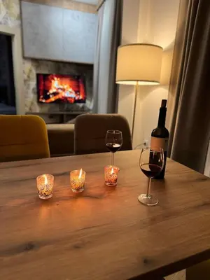 a bottle of wine and two glasses on a wooden table at Friends Apartmani - Broj 2 in Raška
