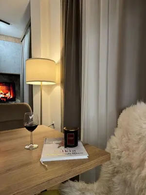 a glass of wine sitting on a table next to a table with a book at Friends Apartmani - Broj 2 in Raška