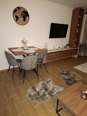 a living room with a table and chairs and a television at Sunčana planina apartman 104 in Kopaonik