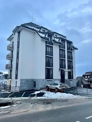 a building with a car parked in front of it at Apartman Lawa Kopaonik in Kopaonik