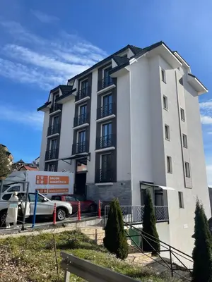 a white building with a car parked in front of it at Apartman Lawa Kopaonik in Kopaonik
