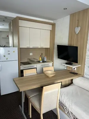a kitchen with a wooden table and a white refrigerator at KONACI Ana Apartman in Kopaonik
