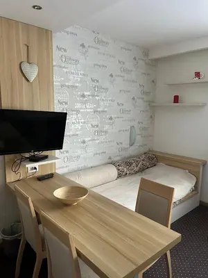 a room with a bed and a desk with a table at KONACI Ana Apartman in Kopaonik