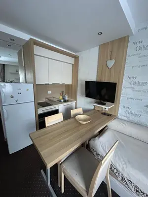 a kitchen with a wooden table and a refrigerator at KONACI Ana Apartman in Kopaonik