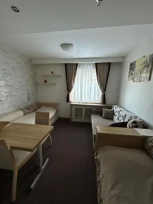 a hotel room with two beds and a table at KONACI Ana Apartman in Kopaonik