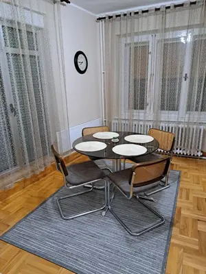 a dining room with a table and chairs and a clock at Apartman Dream M Zaječar in Zaječar