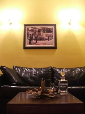 a leather couch with a table and a picture on the wall at Vila Lira in Vrnjačka Banja